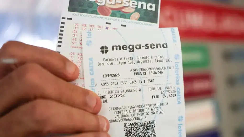 Dedos de um homem segurando papel da aposto na mega-sena.