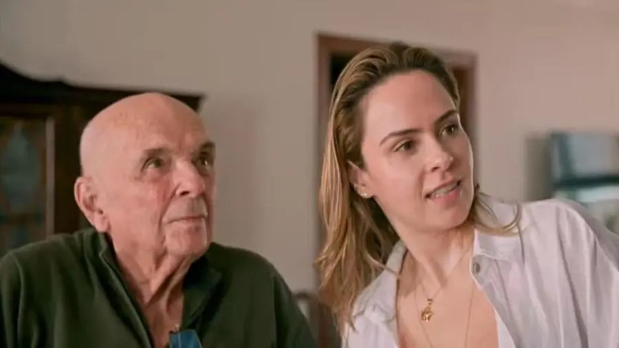 Ana Paula Renault conversando com o pai, Geraldo Renault, em ambiente interno, demonstrando interação e atenção entre eles.