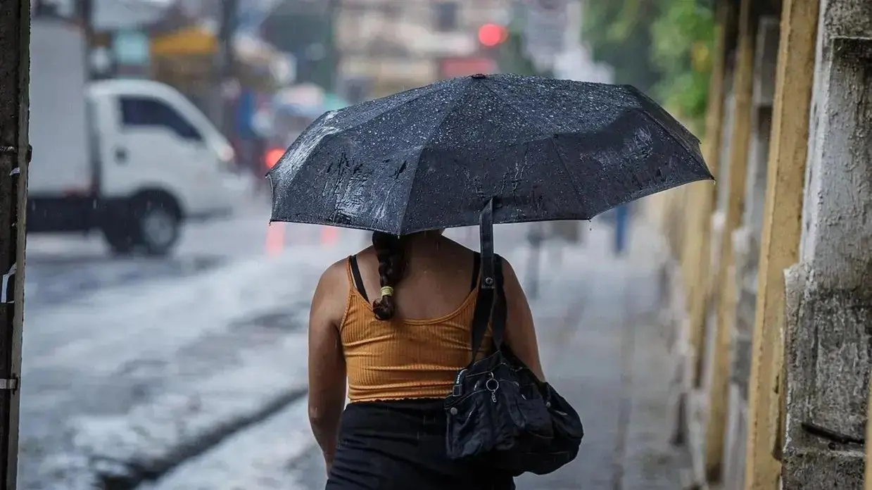 foto de mulher de costas segurando um guarda-chuva preto.