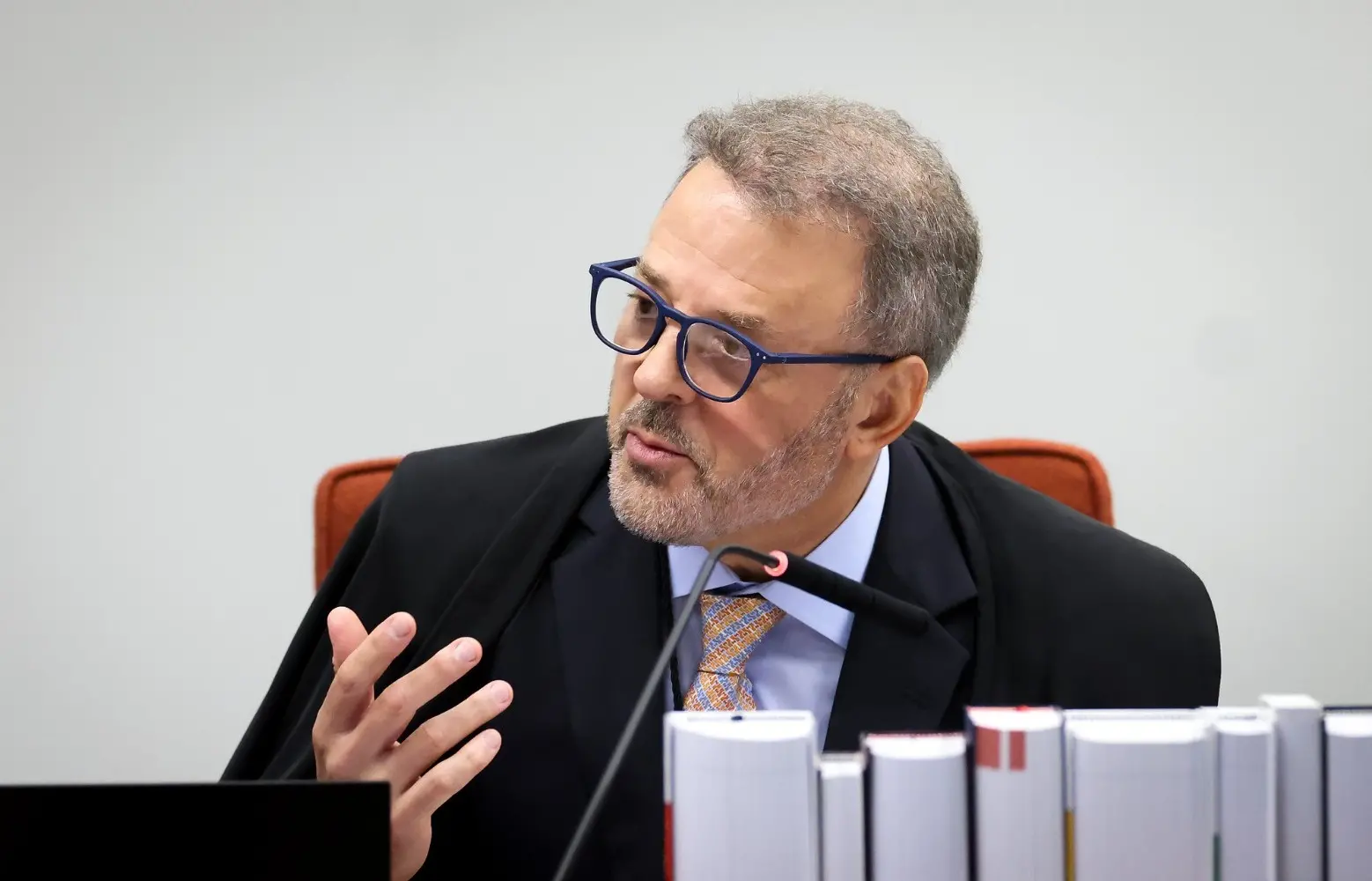 Hindemburgo Chateaubriand gesticula enquanto discursa no STF. Ele é um homem de meia idade, calvo, de cabelo e barba grisalhos. Usa óculos de armação grossa e quadrada na cor azul.