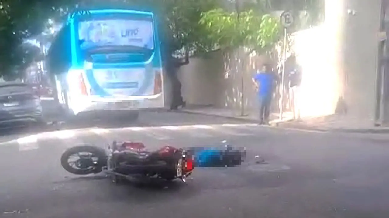 Motocicleta no chão atrás de ônibus.