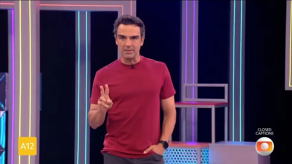 Tadeu Schmidt é um homem branco alto de cabelo preto e que, na foto, usa camisa vermelha.