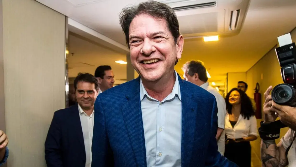 Cid Gomes caminha em direção à câmera. Ao lado dele, aliados também seguem na mesma direção. Ele veste um blazer.