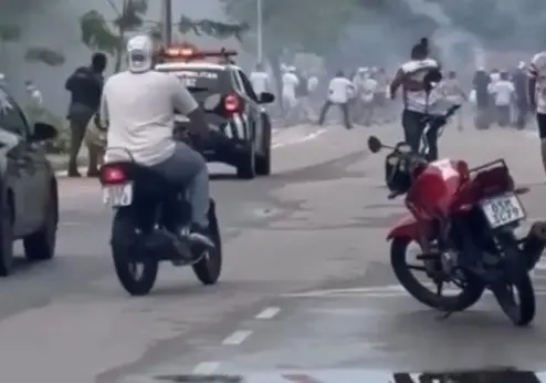 Imagem de torcedores de torcidas organizadas do Fortaleza e do Ceará brigando em via pública em Fortaleza. Há policiais na cena também.