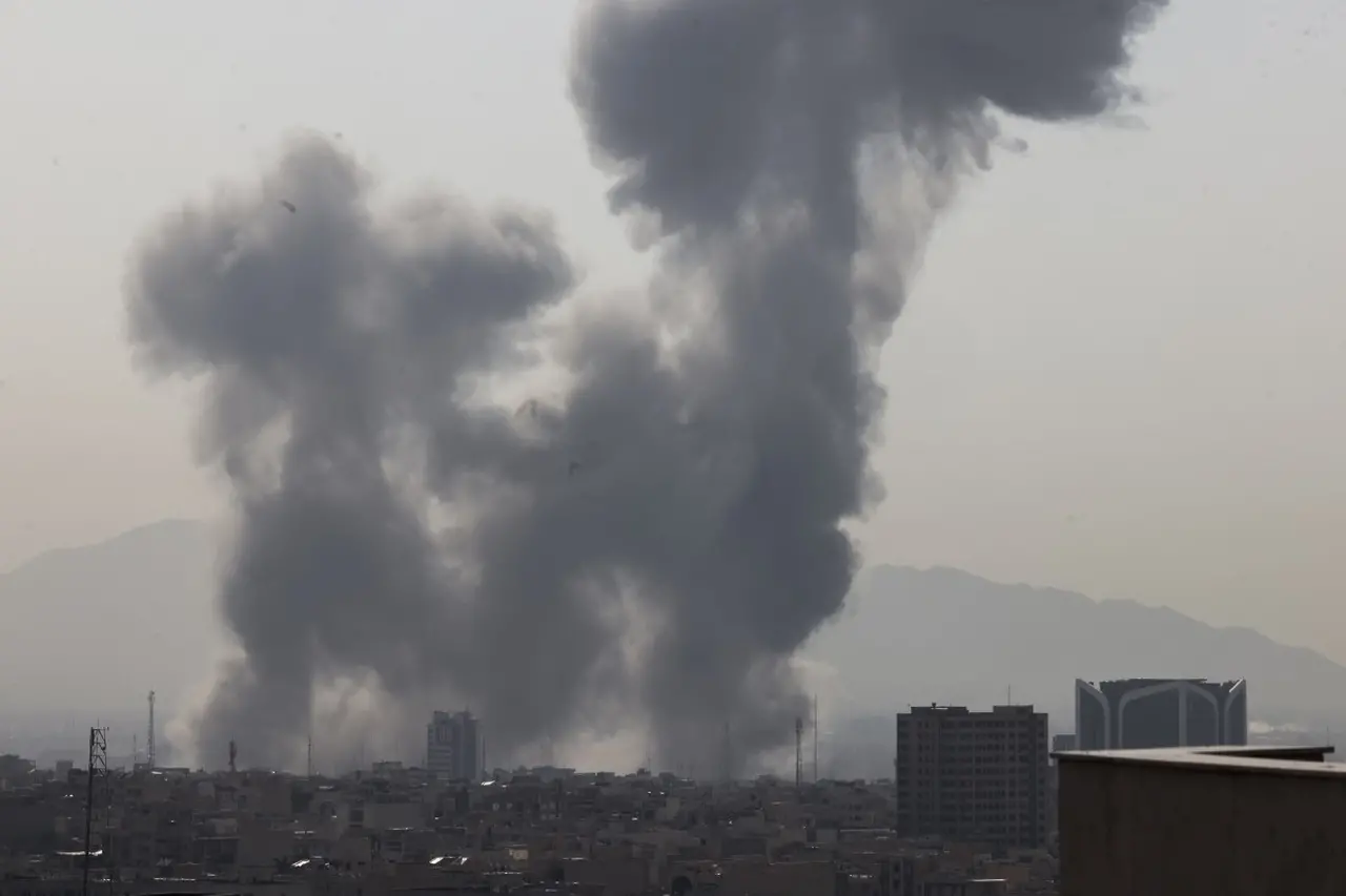 Imagem de céu cinzento com fumaça de explosão acima de prédios baixos.