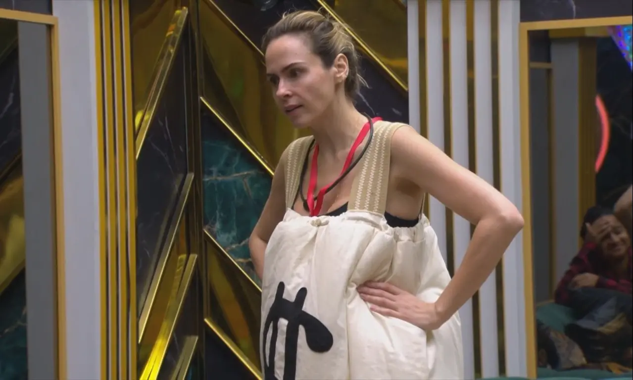 Ana Paula Renault com macacão grande com um cifrão desenhado do monstro da semana.