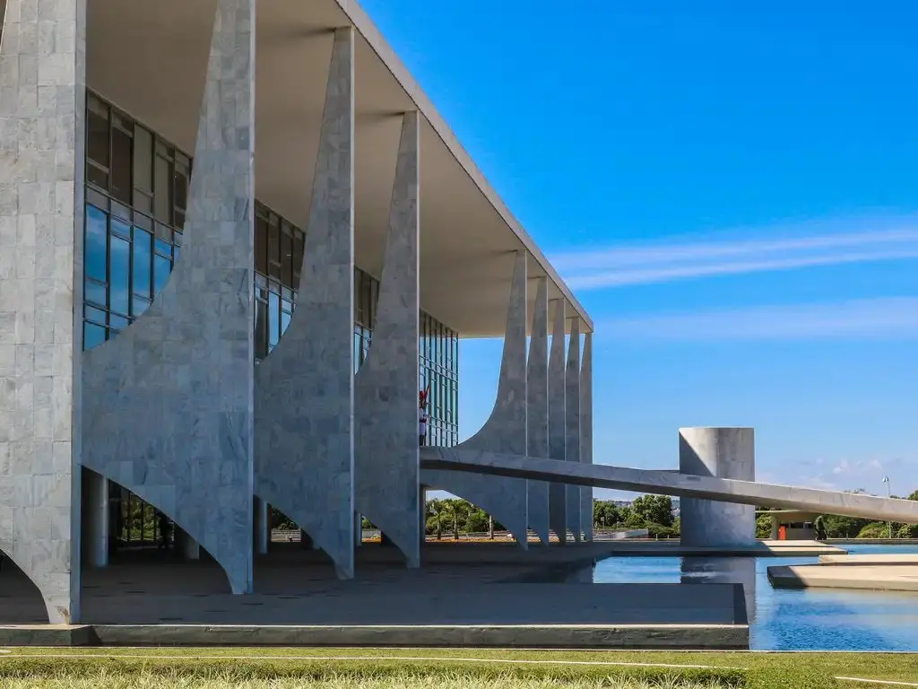 Frente de Palácio do Planalto, com estrutura cinza e céu azul ao fundo.