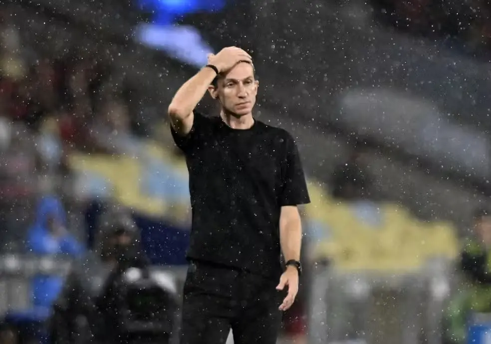 Fotografia de Filipe Luís, ex-técnico do time do Flamengo, onde está parado na chuva e levanta a mão para a testa, em sinal de desespero, em jogo pela recopa sulamericana contra o time argentino Lánus