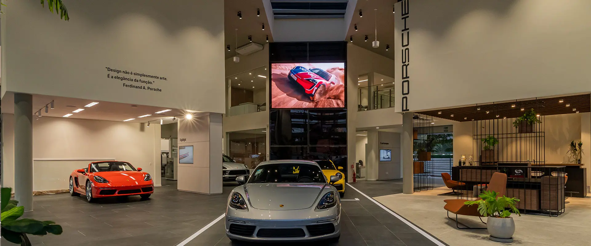 Parte interna da concessionária da Marca Porsche em Fortaleza mostra dois carros no salão em destaque.
