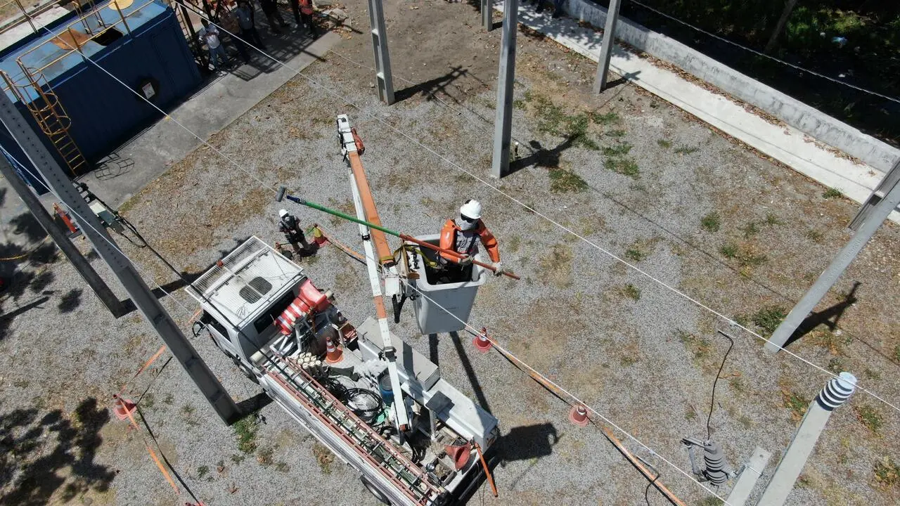 Equipe da Enel realizando manutenção em rede elétrica de média tensão com caminhão munido de cesto aéreo em subestação ao ar livre.