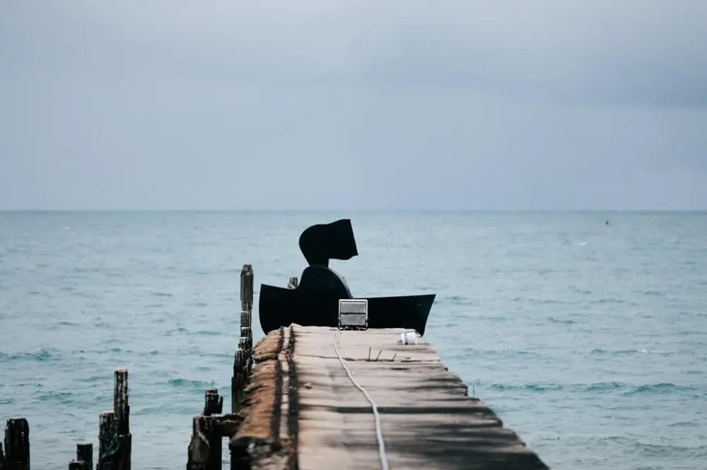 Na imagem, fotografia de plano médio de uma escultura de silhueta preta intitulada 