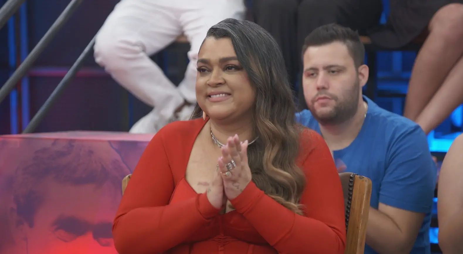 Preta Gil no programa Altas Horas, da Globo. Ela era uma mulher negra de pele clara e cabelo castanho claro ondulado. Na foto, está com blusa colada vermelha e com as palmas das mãos juntas.
