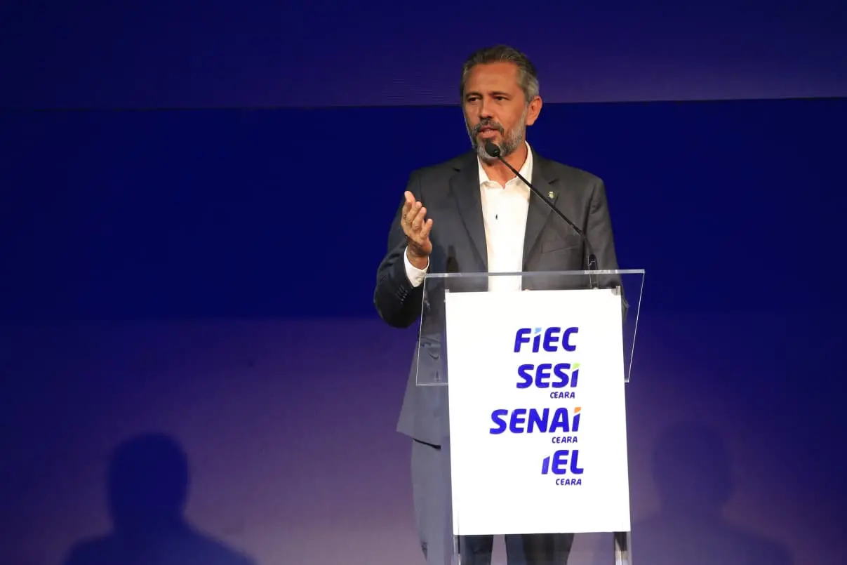 Governador do Ceará fala em palco, em púlpito que traz a logo de setores da indústria.