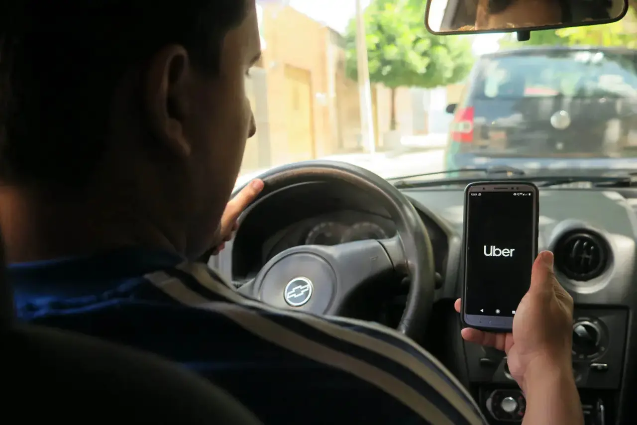 Foto de motorista de aplicativo dentro de veículo.