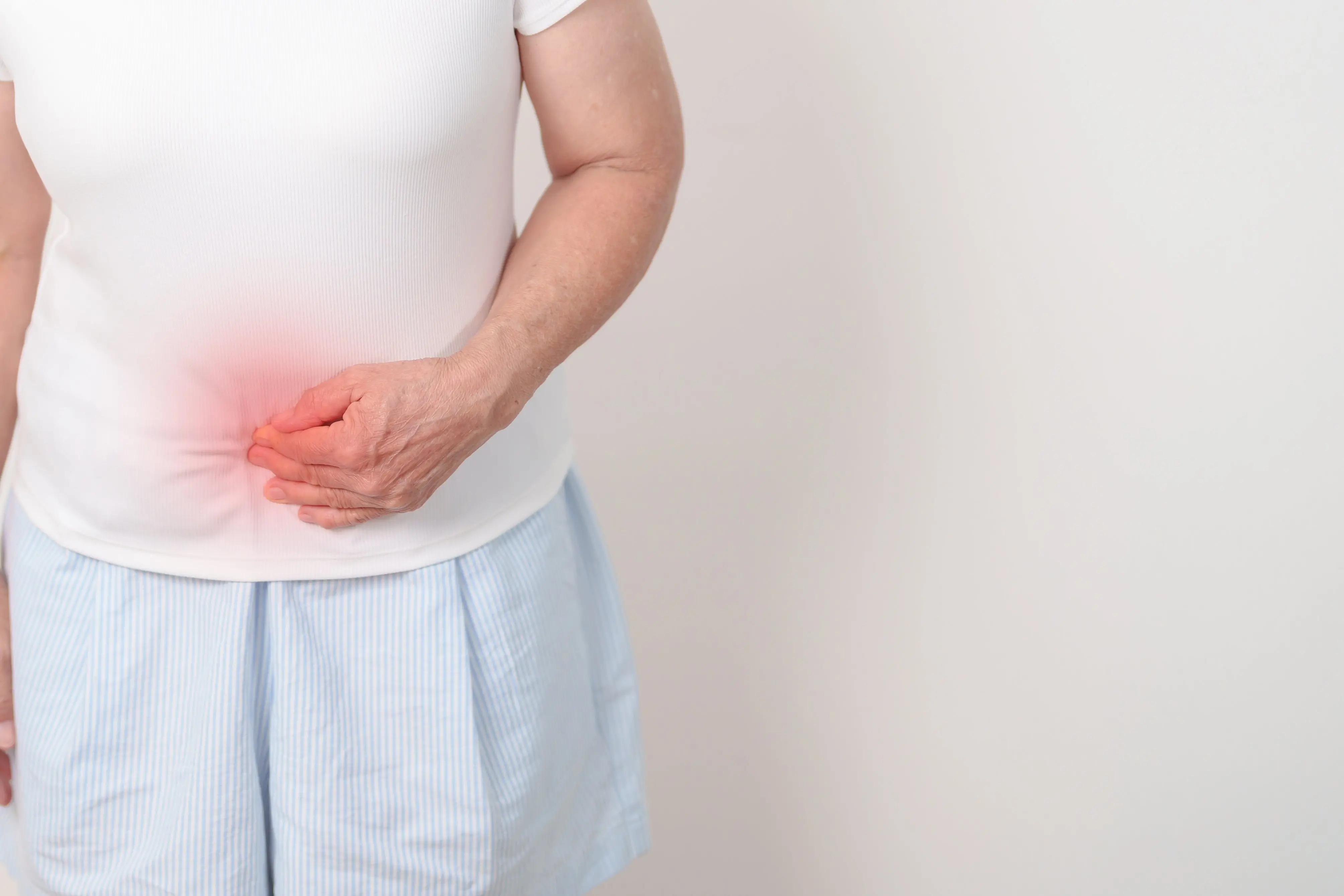 Imagem de uma mulher sentindo dor para matéria sobre prevenção ao câncer colorretal.