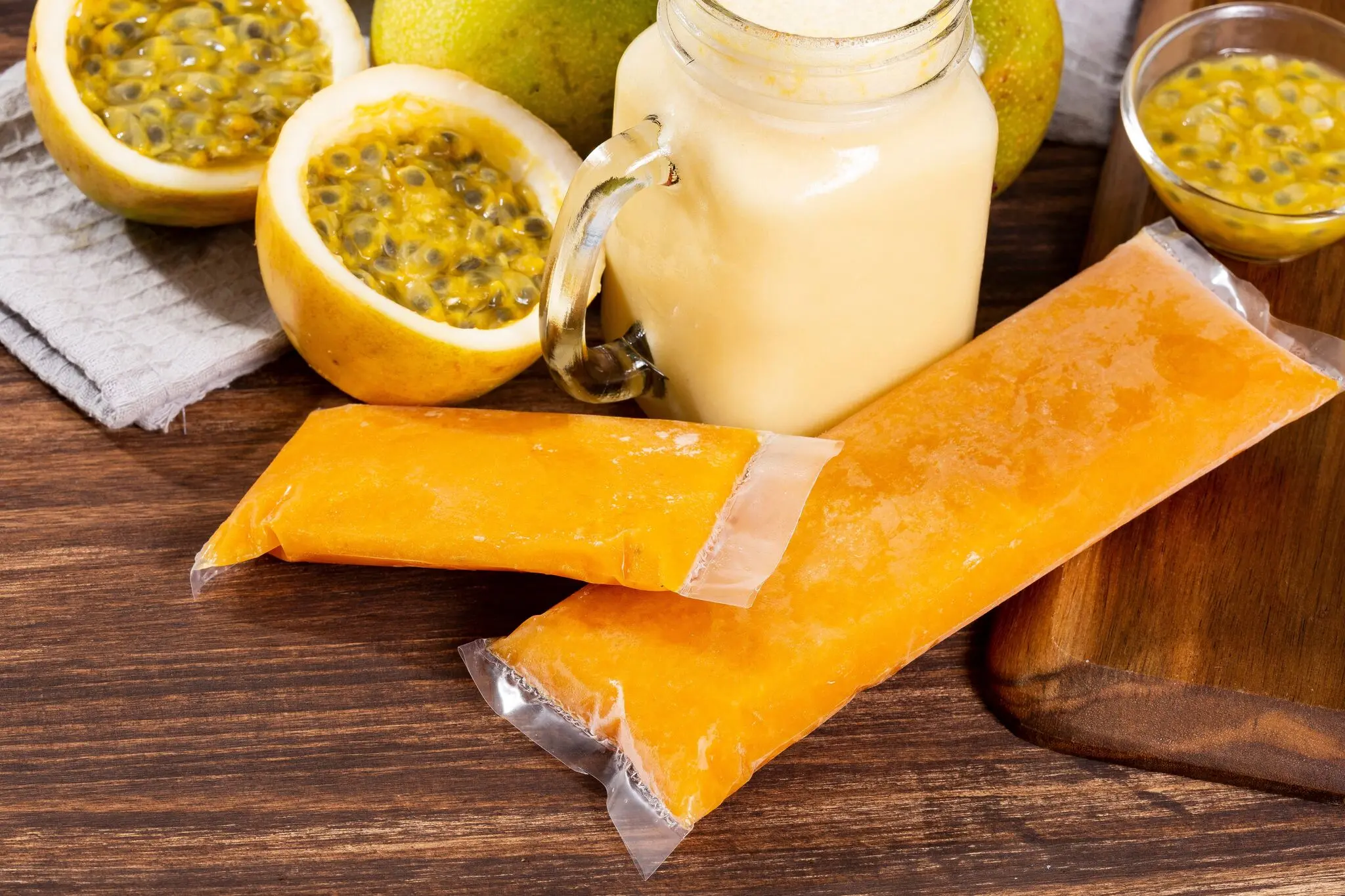 Polpa de maracujá ao lado de pedaços da fruta cortada e de vitamina feita com a fruta.