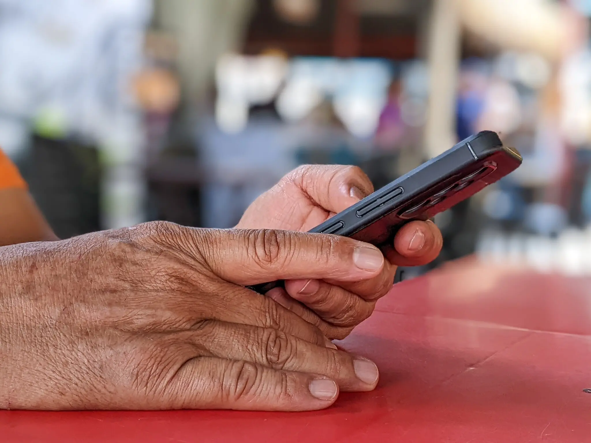 Mãos de homem idoso usando celular.
