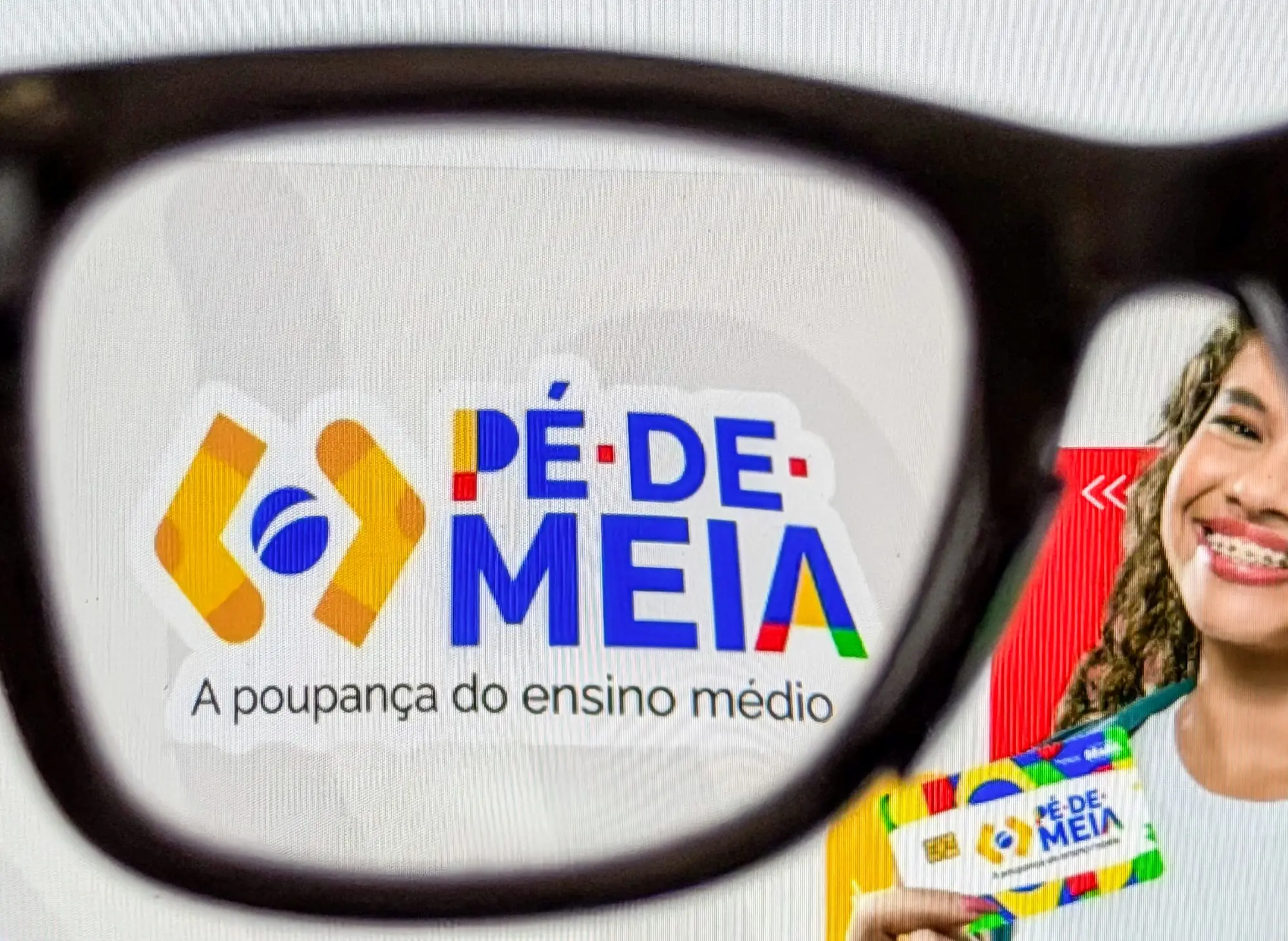 Logo do programa Pé-de-Meia: A poupança do ensino médio exibido através de óculos, com uma estudante sorrindo e segurando o cartão do benefício.
