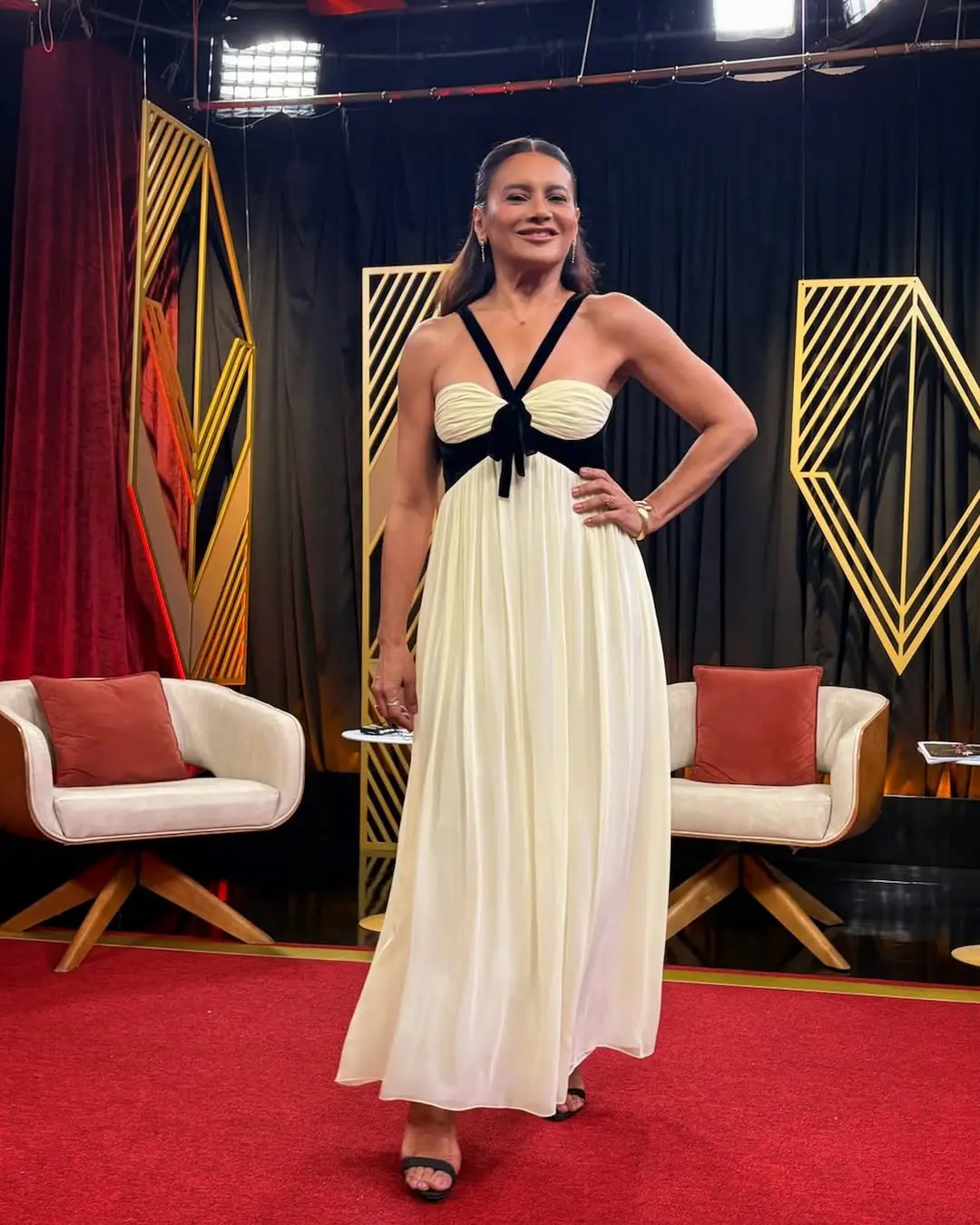 Registro de Dira Paes usando vestido de gala em cenário de cobertura do Oscar em 2025.