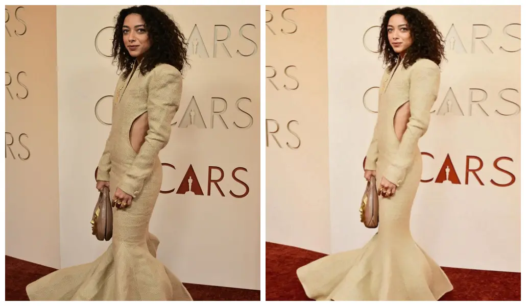 Atriz Alice Carvalho no tapete vermelho do Oscar. Ela está de cabeo cacheado solto. Veste um vestido longo de cor clara e posa para foto de lado, mostrando decote na cintura.