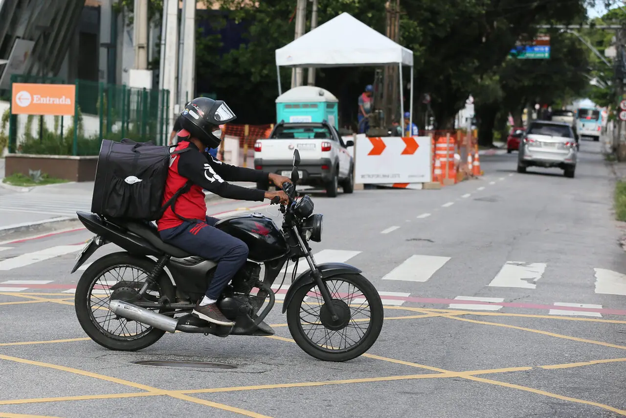 Foto de entregador de aplicativo a caminho de entrega em rua de Fortaleza.