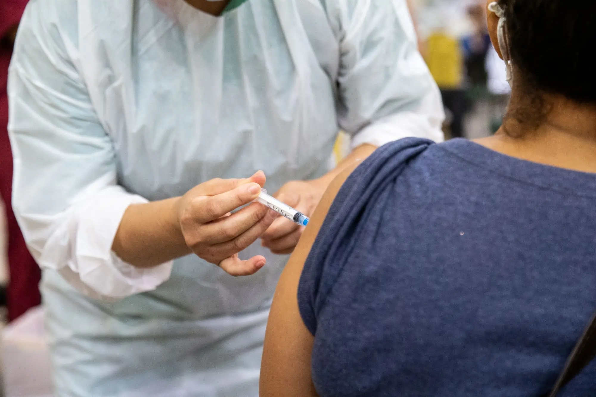 Profissional de saúde administrando uma vacina no braço de uma pessoa.