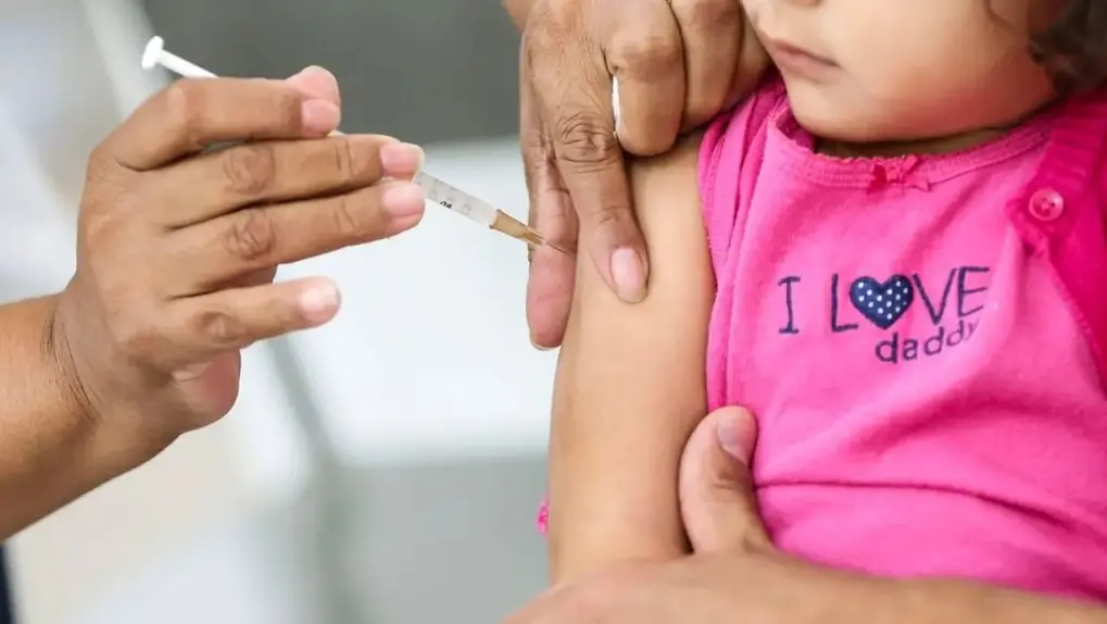 Criança recebendo vacina da inflouenza na braço com orientação de profissional de saúde para imunização contra doenças. Processo de vacinação infantil.