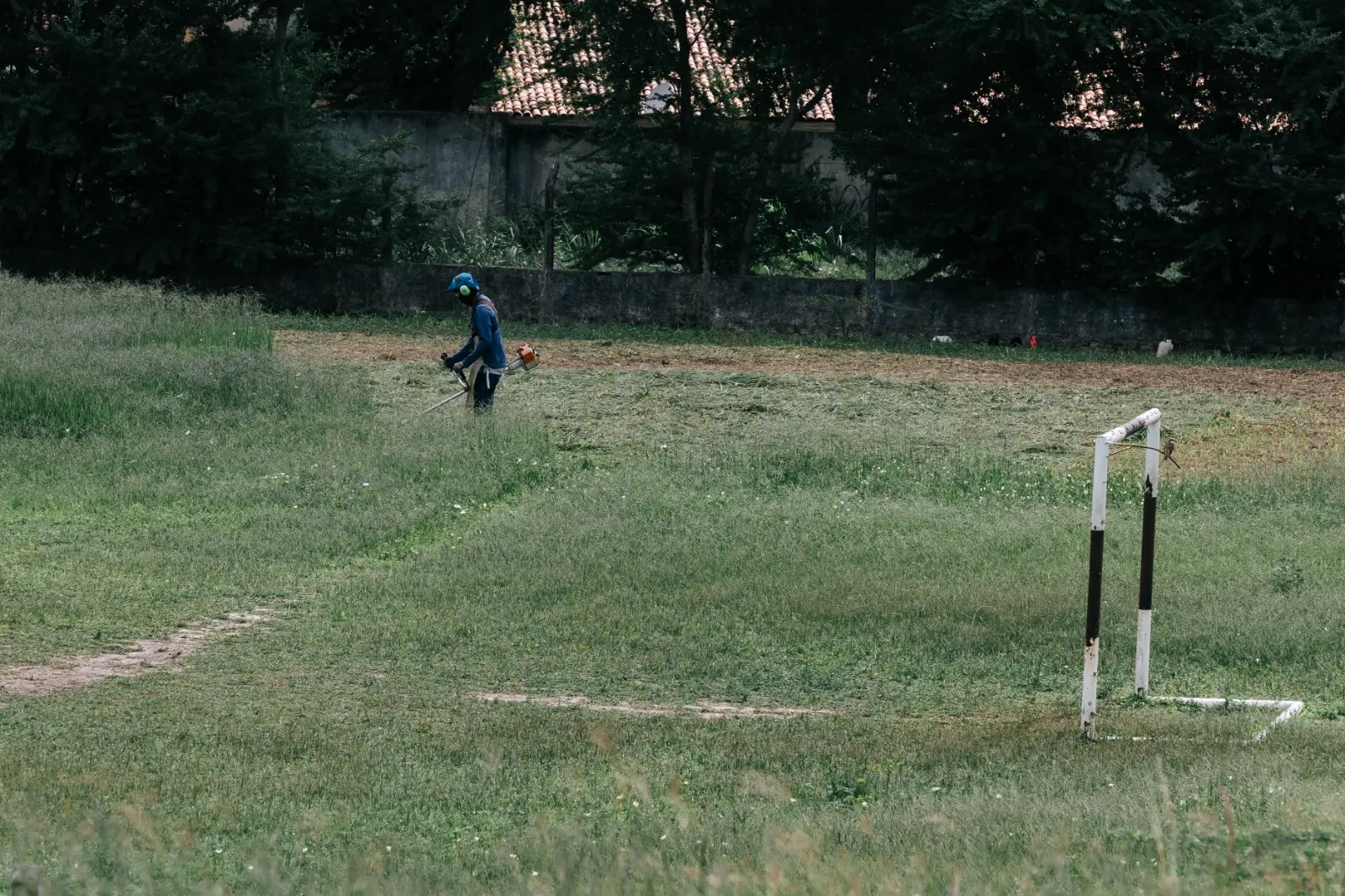 Imagem mostra funcionário aparando grama alta do campo de futebol do Instituto de Educação Física e Esportes (Iefes) da UFC, em Fortaleza.
