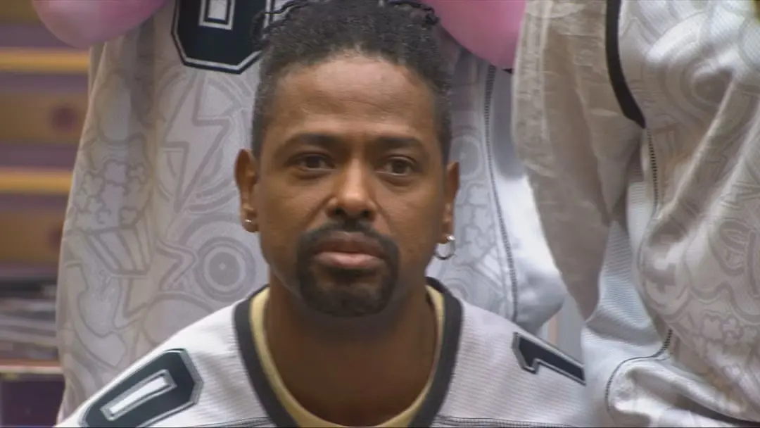 Leandro Boneco olha para a câmera. Ele veste um colete branco.