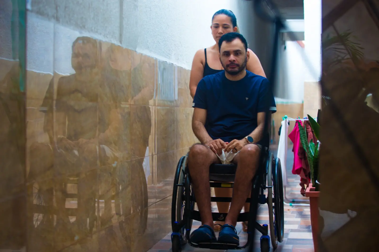 Mulher ajuda homem de cadeira de rodas.