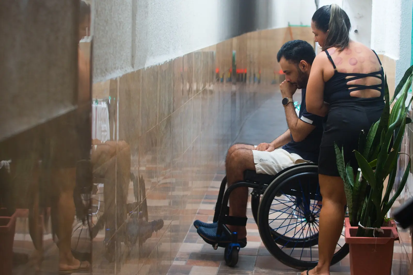 Mulher ajuda homem de cadeira de rodas.