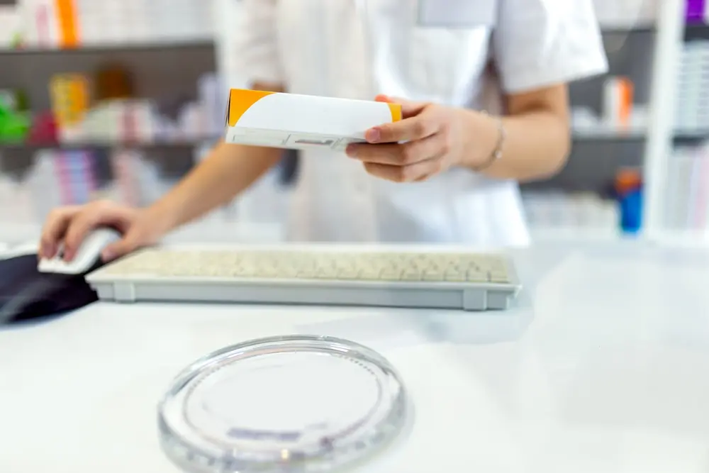 foto mostra funcionária registrando produto em caixa de farmácia.
