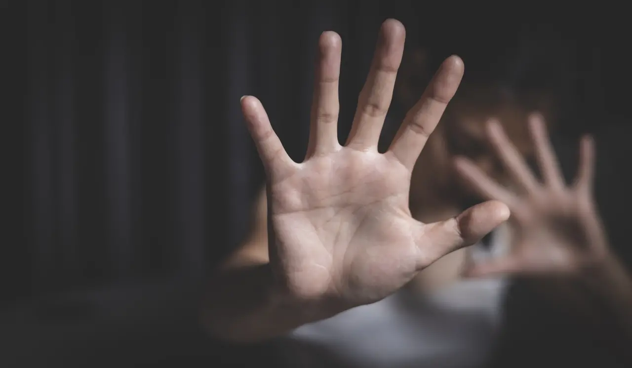 Uma mão estendida em primeiro plano faz um gesto de 