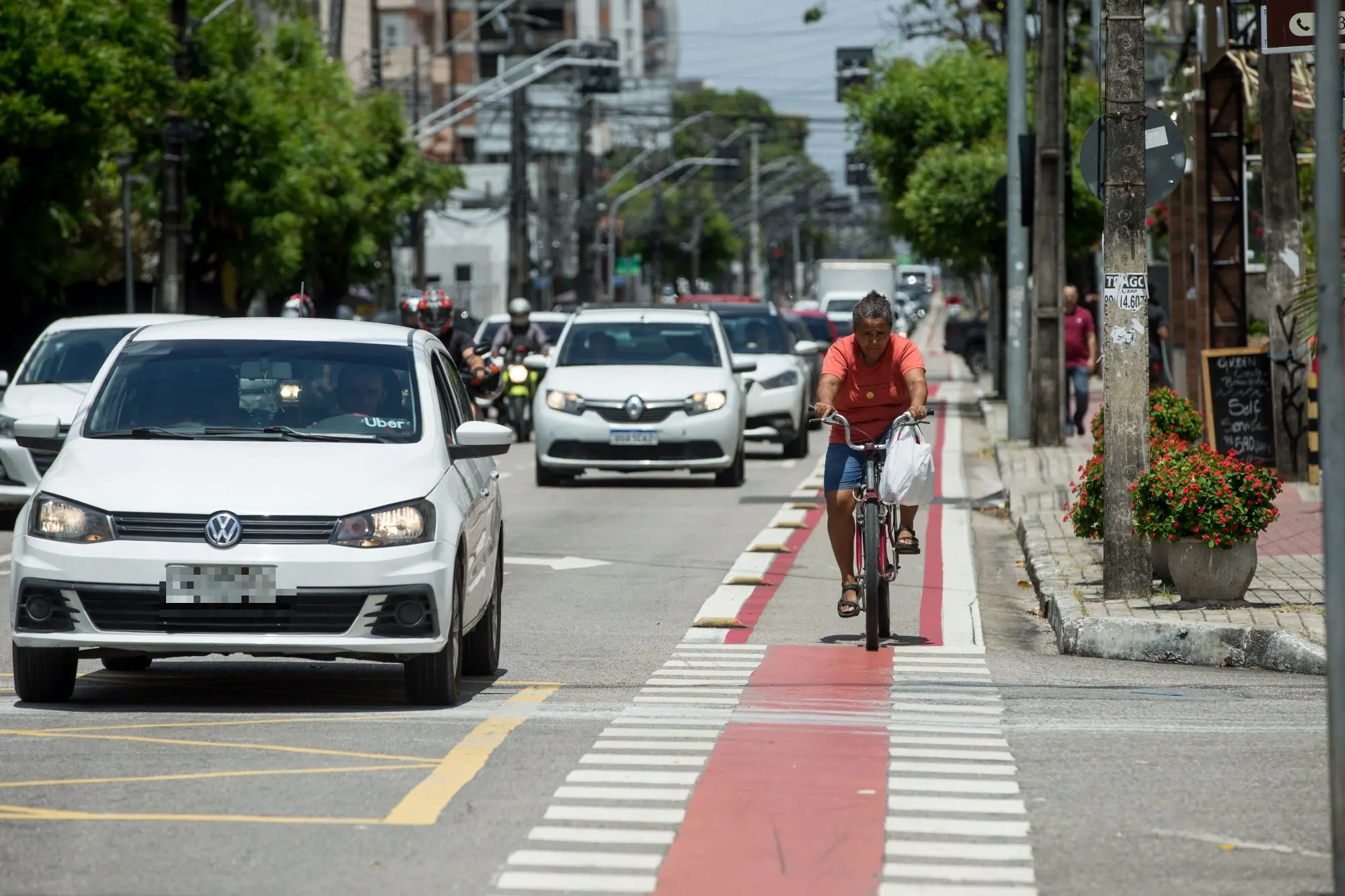 pessoa pedalando em ciclofaixa, ao lado de carros.