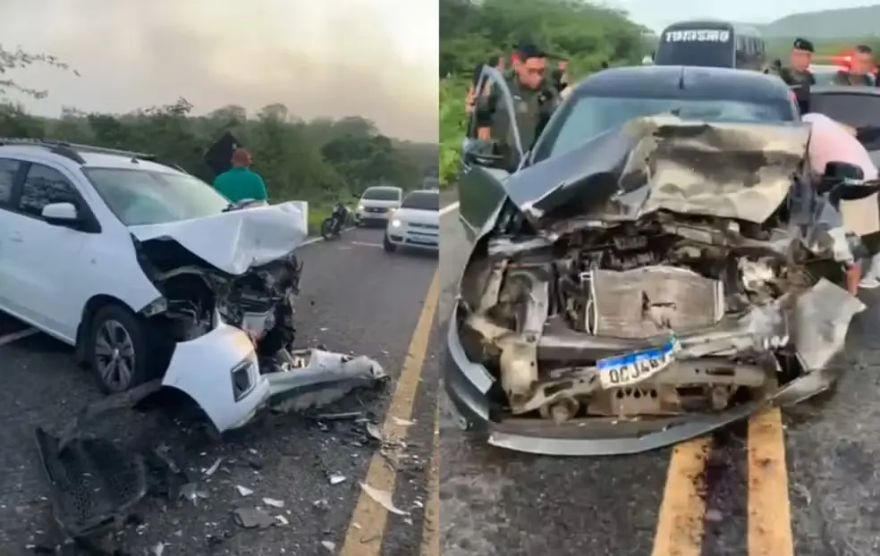 Dois carros aparecem com as frentes totalmente destruídas após uma colisão frontal em uma rodovia, com destroços espalhados pelo asfalto. Policiais e civis cercam os veículos danificados em um cenário de final de tarde sob o céu nublado.