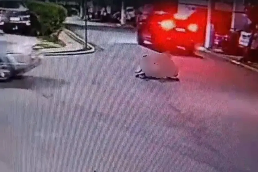 Imagem de uma rua movimentada com carros e um veículo se aproximando, capturada por uma câmera de segurança, com foco na esquina e trânsito intenso.