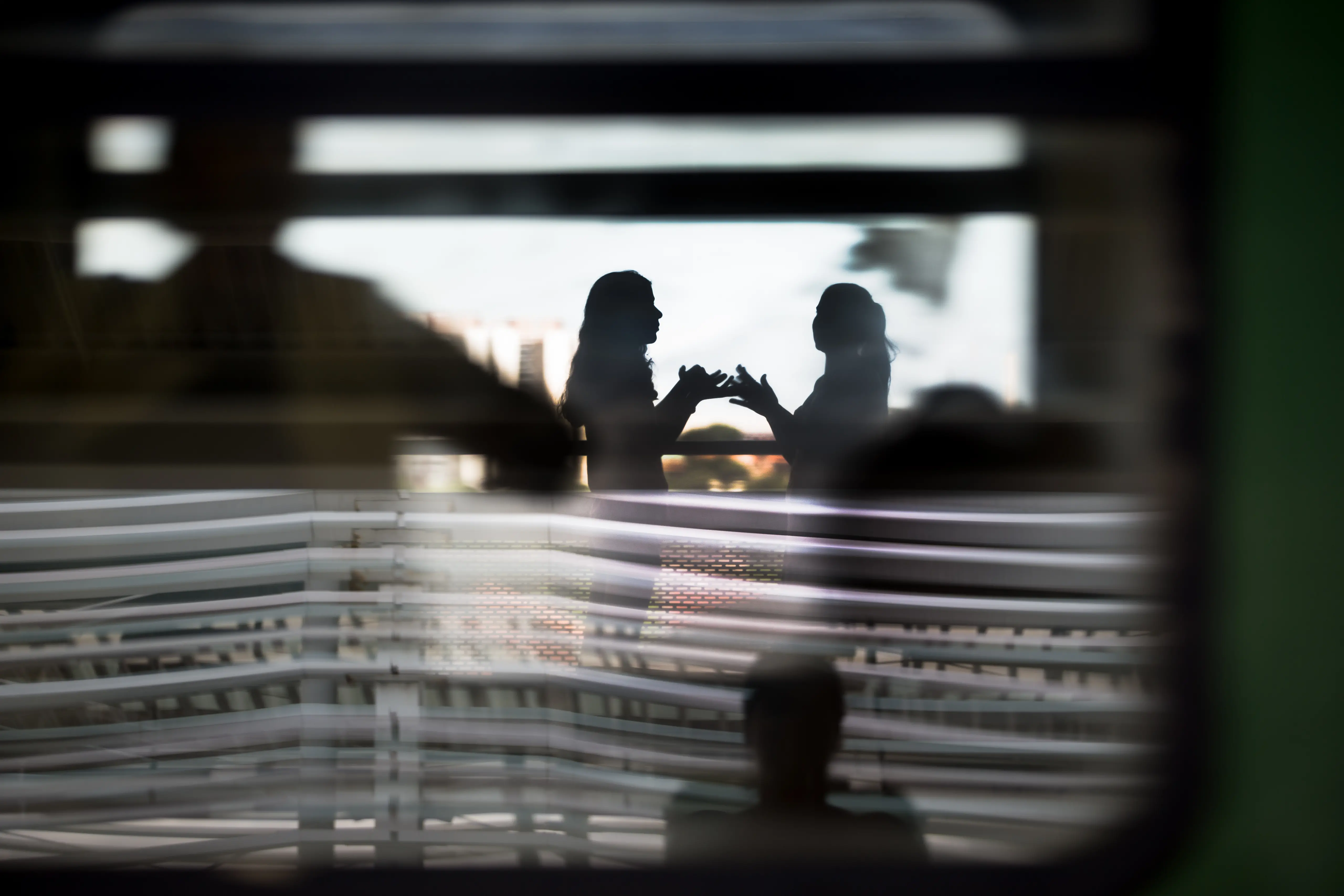 Duas silhuetas brincando com as mãos. 