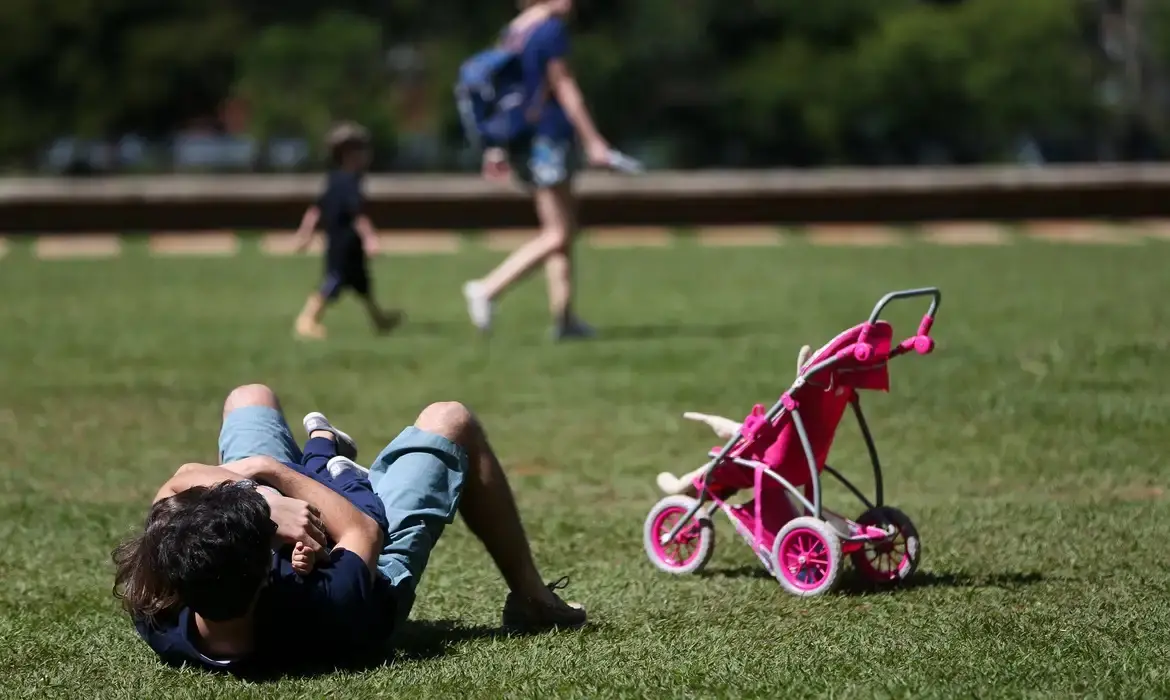Pai e filho brincando em gramado.