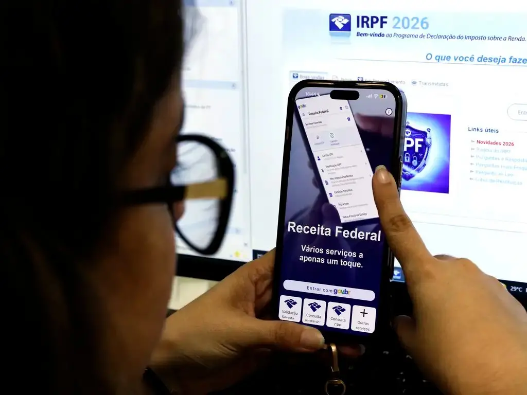 Mulher mexe no celular, em aplicativo da Receita Federal.