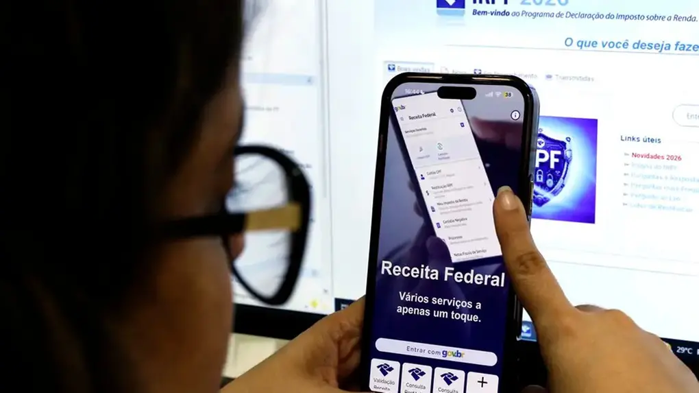 Mulher mexe no celular, em aplicativo da Receita Federal.