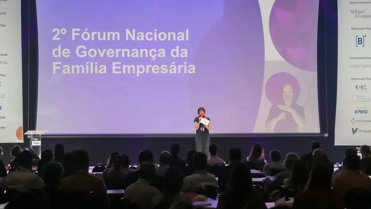 Auditório com público assistindo apresentação no 2º Fórum Nacional de Governança da Família Empresária, com palestrante no palco.