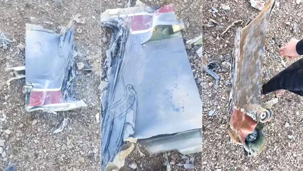 Na imagem, foto de baixa resolução capturada de um vídeo em um ambiente interno, possivelmente um restaurante ou bar. No centro, um homem de pele clara, vestindo uma camisa polo azul-marinho e calças claras, está em uma pose curvada com os joelhos dobrados e braços abertos para os lados. Ele tem uma expressão facial de surpresa ou exclamação, com a boca aberta. Outras pessoas aparecem parcialmente desfocadas em primeiro plano e ao fundo, sugerindo um momento de movimento ou interação social.