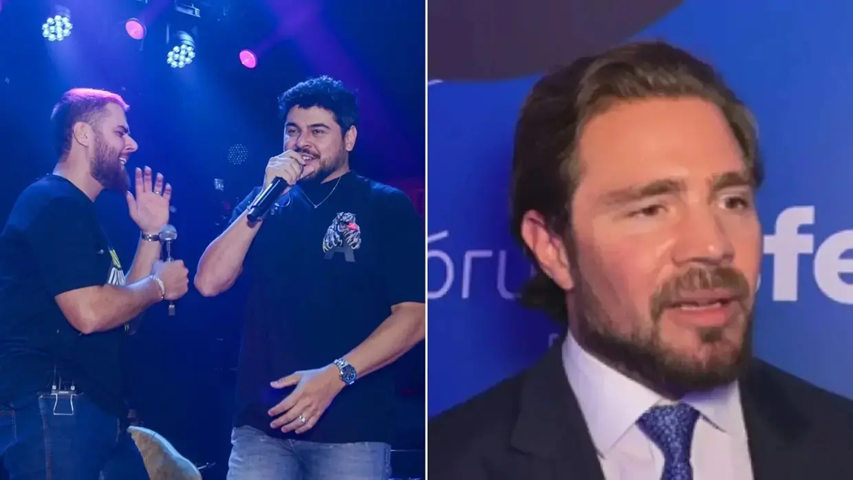 Os cantores Zé Neto e Cristiano se apresentam em um palco iluminado por luzes azuis e roxas. À direita, uma imagem aproximada destaca o empresário Daniel Vorcaro usando terno escuro e gravata azul em frente a um painel publicitário.