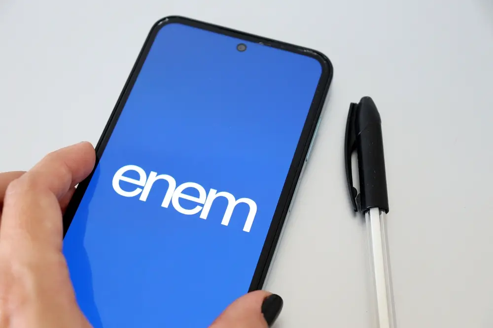 Imagem de um smartphone com a tela exibindo o logo da plataforma Enem, ao lado de uma caneta preta, simbolizando preparação para o exame.