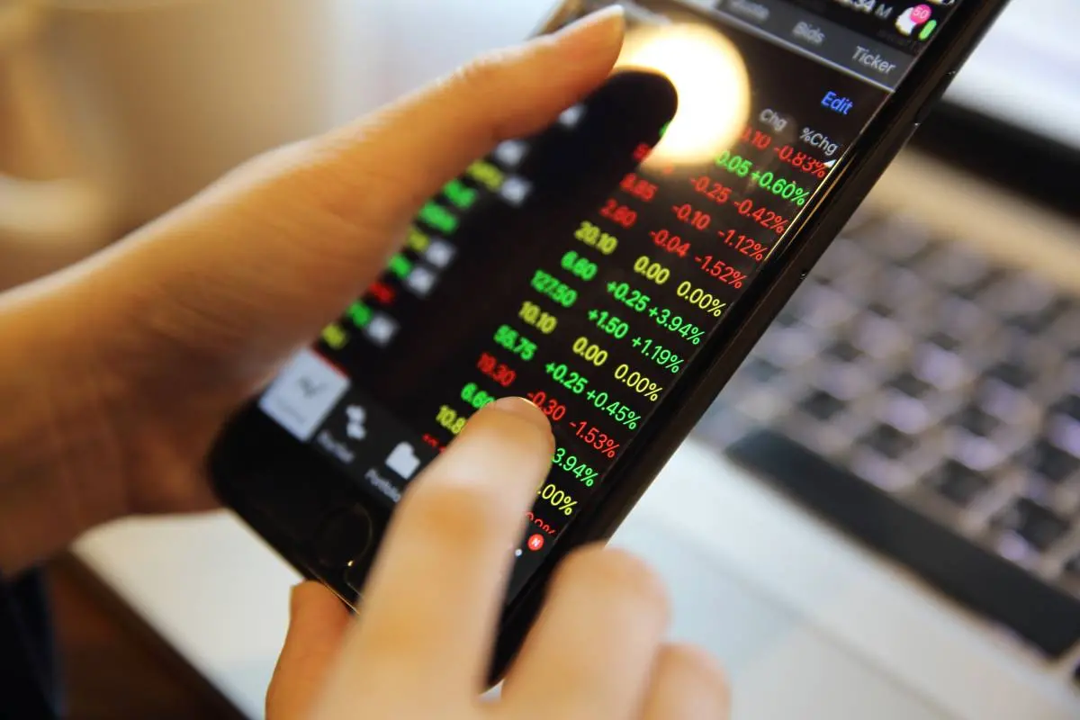 Imagem mostra a mão de uma pessoa conferindo o lucro da criptomoeda no celular.