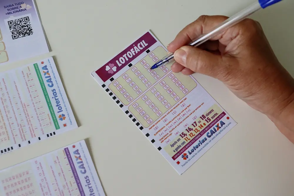 Pessoa marca números em uma aposta de loteria Caxia com um caneta azul, ao lado de bilhetes de loteria e detalhes de apostas, promovendo a sorte e a diversão com jogos de azar.
