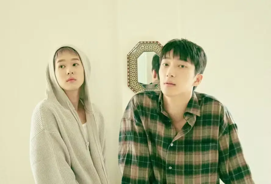 Jovens em estilo casual posando em ambiente com espelho decorativo ao fundo, expressão pensativa e estilo fashion moderno.