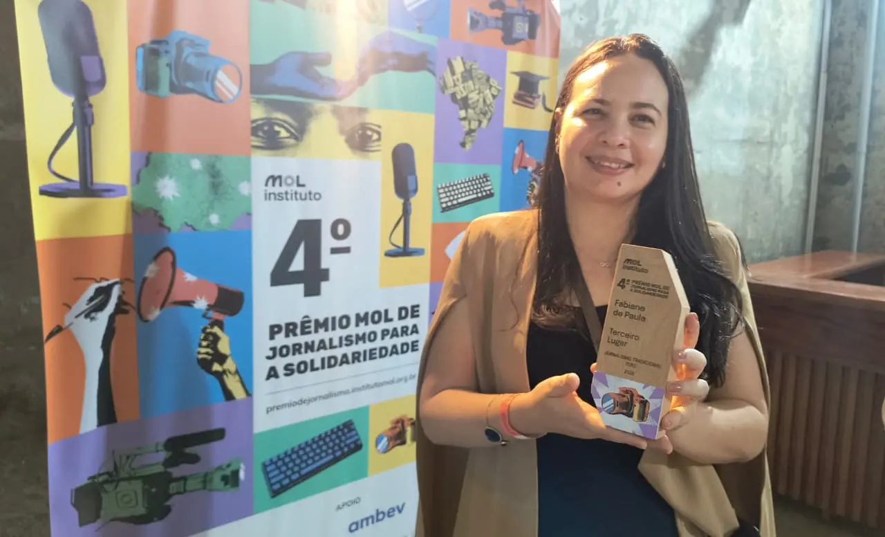 Fabiane de Paula segurando o prêmio recebido no Prêmio MOL de Jornalismo.