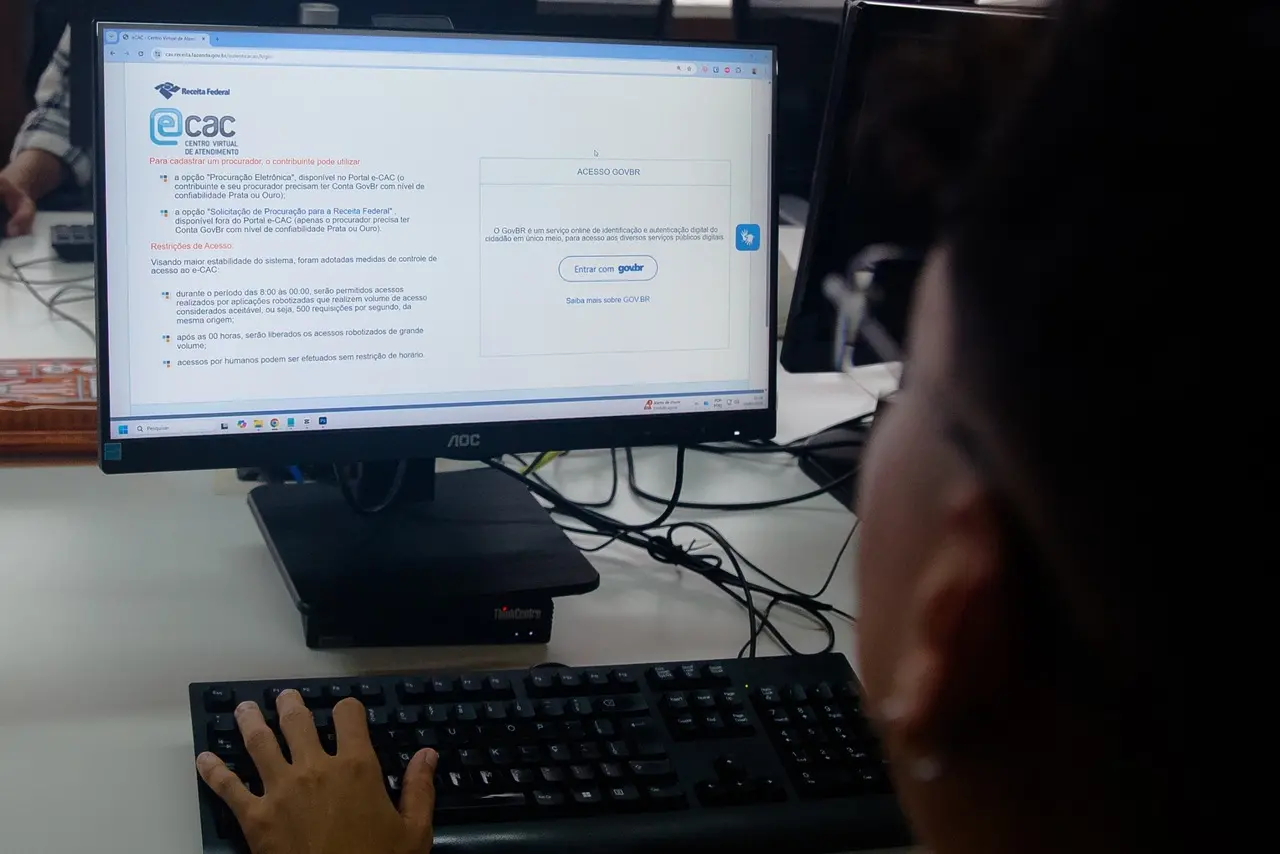 Pessoa acessa o sistema e-CAC da Receita Federal em um computador para consultar informações fiscais e pendências do Imposto de Renda.