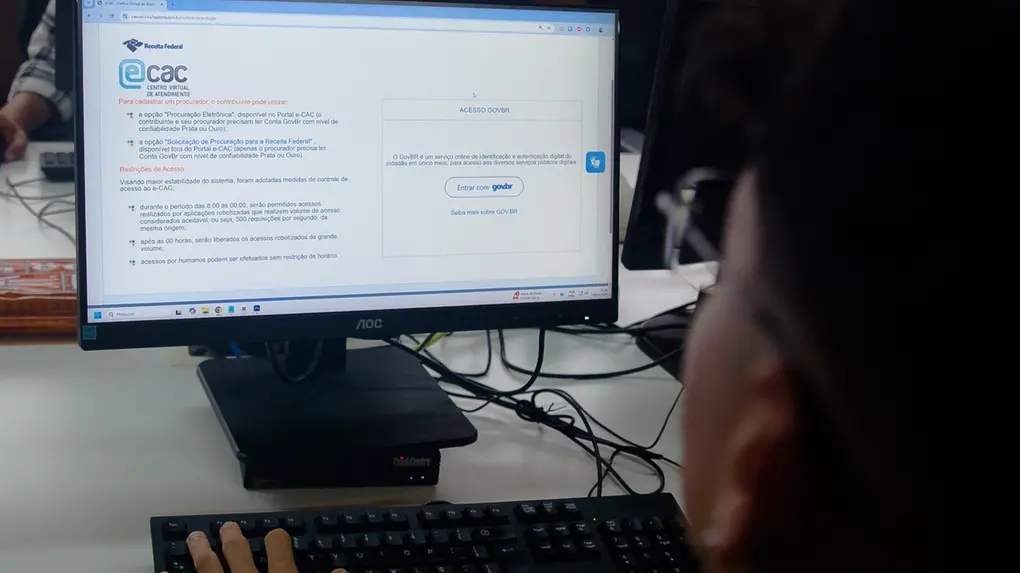 Pessoa acessa o sistema e-CAC da Receita Federal em um computador para consultar informações fiscais e pendências do Imposto de Renda.
